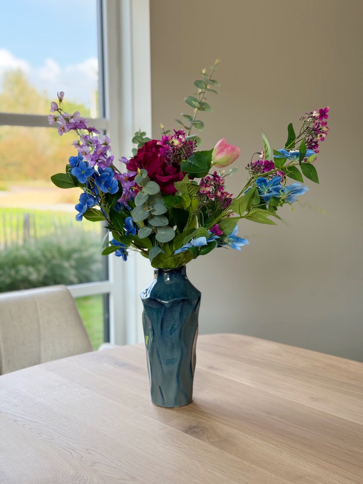 blauwe vaas met blauw zijden bloemen boeket